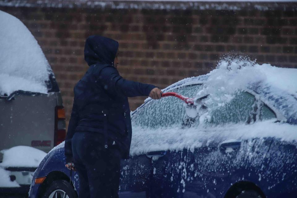 A pedestrian removes snow from her car on Thursday, Nov. 15, 2018, in Wilmington.