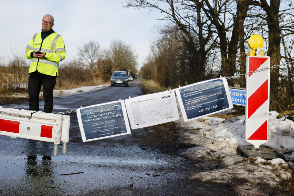 A Danish police officer guards a closed border crossing near Handewitt, Germany, Saturday, Feb. 20, 2021. Denmark has closed several smaller border crossings to Germany because of the coronavirus situation in the region near the city of Flensburg. (Frank Molter/dpa via AP)