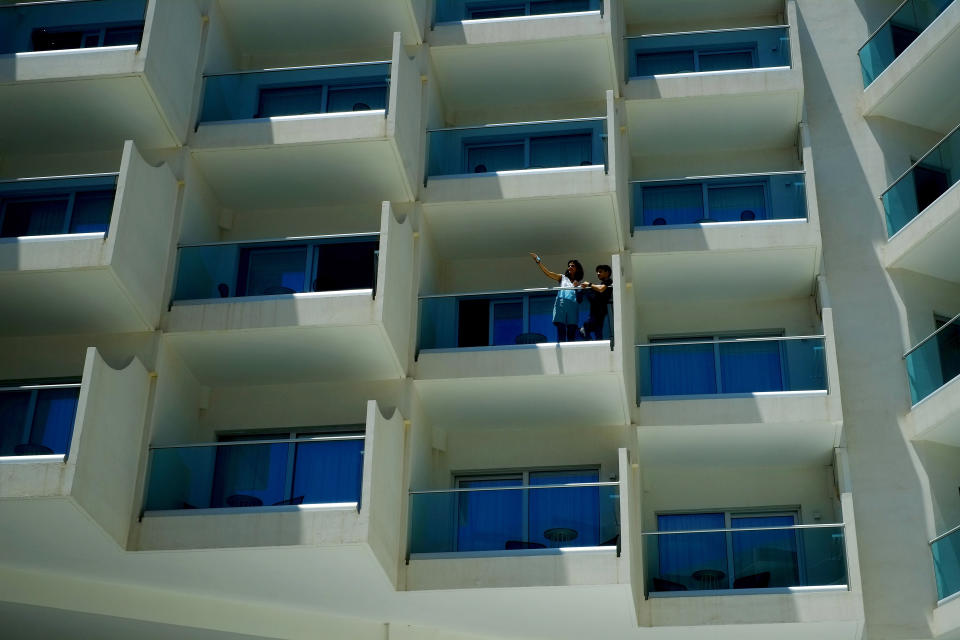 A woman and a boy stand at a balcony of a room of Nissi Blue hotel in southeast resort of Ayia Napa, in the eastern Mediterranean island of Cyprus, Saturday, May 22, 2021. Cypriot hotel and other tourism-related business owners say they'd like to see the COVID-19 pandemic-induced uncertainty over travel bookings to the tourism-reliant island nation winding down by July when they're hoping authorities in Cyprus' main markets including the U.K., Russia, Germany and the Scandinavian countries will make it easier for their citizens to travel abroad. (AP Photo/Petros Karadjias)