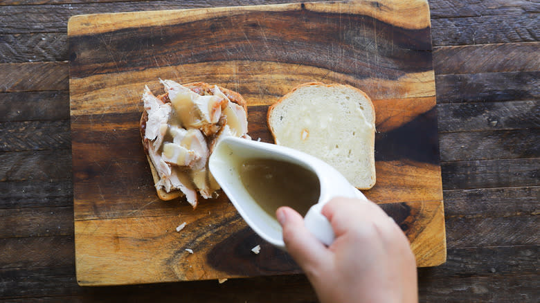 Pouring gravy on turkey sandwich