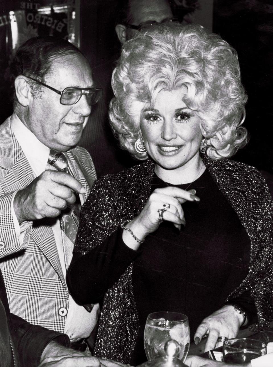 <p>In 1977, Dolly Parton had climbed the charts with hits like "Jolene, "I Will Always Love You," and "Coat of Many Colors." She was on the cusp of making the transition to pop-country crossovers as more leaders in the industry began to realize her star potential. Here, she sparkles at an RCA party with iconic agent Lee Solters. </p>