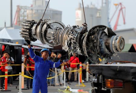 FILE PHOTO: A worker assists his colleague as an turbine engine of Lion Air flight JT610 is lifted up at Tanjung Priok port in Jakarta