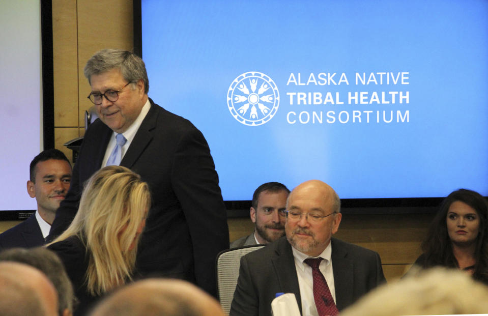 FILE - In this May 29, 2019 file photo U.S. Attorney General William Barr, standing, greets participants at a roundtable discussion at the Alaska Native Tribal Health Consortium in Anchorage, Alaska. Alaska Native villages are receiving almost $5 million from the U.S. Justice Department to combat numerous public safety problems, including no law enforcement presence in some communities. The announcement Tuesday, July 30, 2019, comes nearly two months after Barr met with tribal representatives during a visit to the state who detailed slow response times from authorities, violence against women and abuse of alcohol and drugs, including opioids. (AP Photo/Mark Thiessen, File)