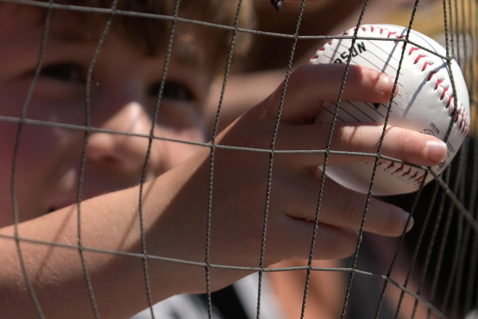 A baseball fan holds a ball as he waits to get an autograph from Chicago White Sox's Jake Burger before a baseball game between the Kansas City Royals and the Chicago White Sox in Chicago, Sunday, May 21, 2023. (AP Photo/Nam Y. Huh)