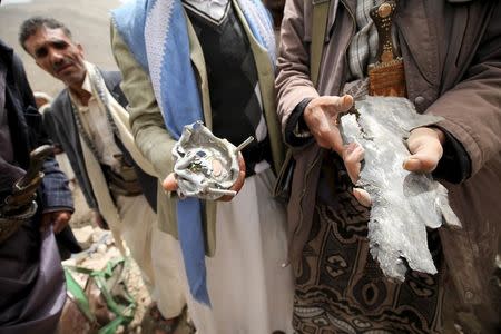 A man shows shrapnel at the rubble of houses destroyed by an air strike in the Okash village near Sanaa April 4, 2015. REUTERS/Mohamed al-Sayaghi