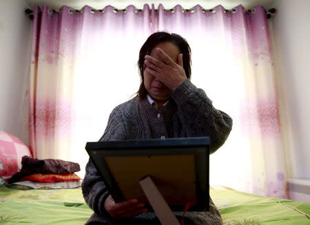 Cui Wenlan cries as she looks at her dead son's picture during an interview with reporters in the house where her son lived in Zhangjiakou, China, November 21, 2015. REUTERS/Kim Kyung-Hoon