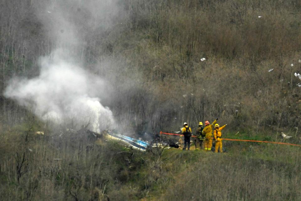 In this Jan. 26, 2020, file photo, firefighters work the scene of a helicopter crash where former Lakers star Kobe Bryant died along with eight others in Calabasas, California.