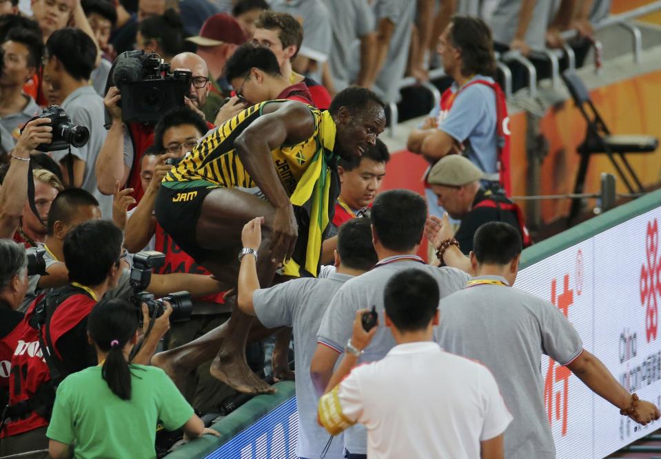 Usain Bolt of Jamaica jumps across an advertising hoarding after winning the men's 200 metres final during the 15th IAAF World Championships at the National Stadium in Beijing