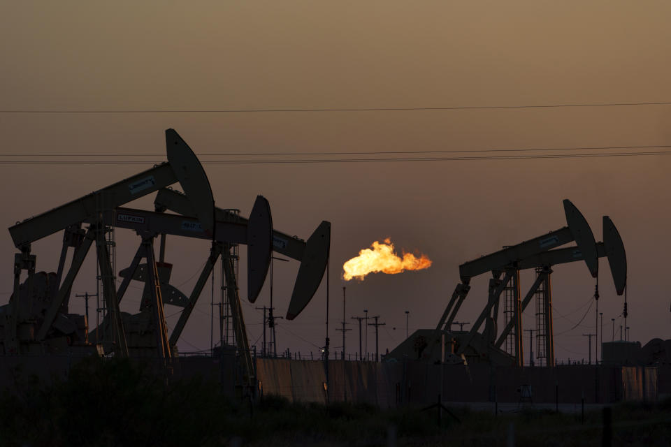 A flare burns off methane and other hydrocarbons as oil pumpjacks operate in the Permian Basin in Midland, Texas, Tuesday, Oct. 12, 2021. Massive amounts of methane are venting into the atmosphere from oil and gas operations across the Permian Basin, new aerial surveys show. The emission endanger U.S. targets for curbing climate change. (AP Photo/David Goldman)