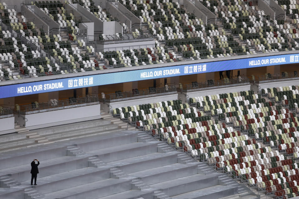 A man takes pictures during a tour at the new National Stadium Sunday, Dec. 15, 2019, in Tokyo. The stadium is officially completed. (AP Photo/Jae C. Hong)