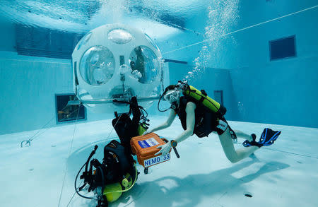 Waitress Valeryia Prusakova brings the dinner in a waterproof box to customers sitting inside "The Pearl", a spheric dining room placed 5 metres underwater in the NEMO33 diving center, one of the world's deepest pools (33 metre/36 yards) built to train professional divers, in Brussels, Belgium January 30, 2017. Picture taken on January 30, 2017 REUTERS/Yves Herman