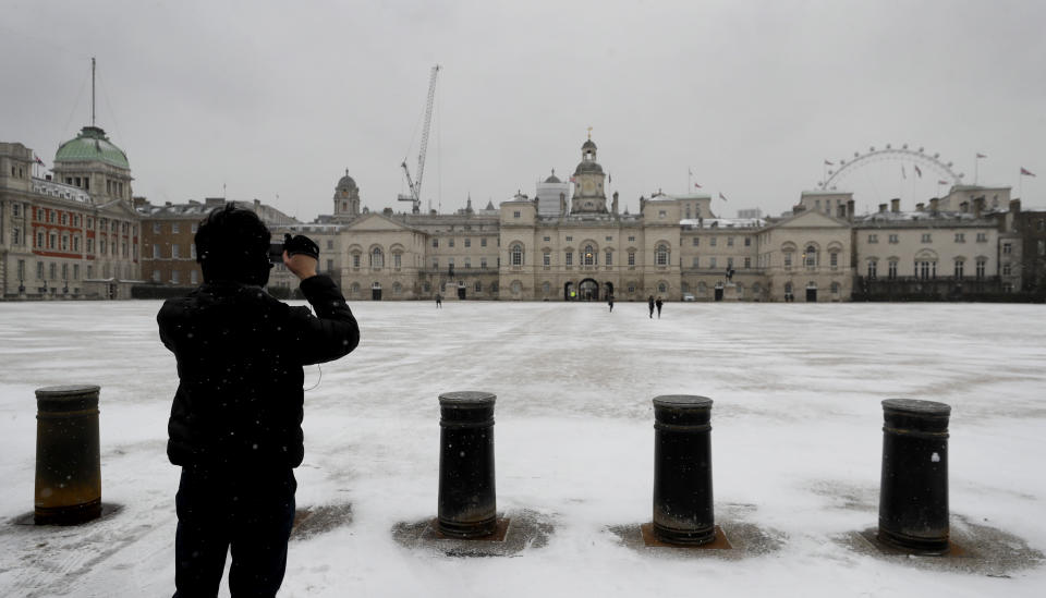 A man photographs snow on Horse Guards Parade as temperatures dropped below freezing in London, Monday, Feb. 8, 2021. Snow has swept across the country, with further snowfall predicted, bringing travel problems as temperatures dropped. (AP Photo/Kirsty Wigglesworth)