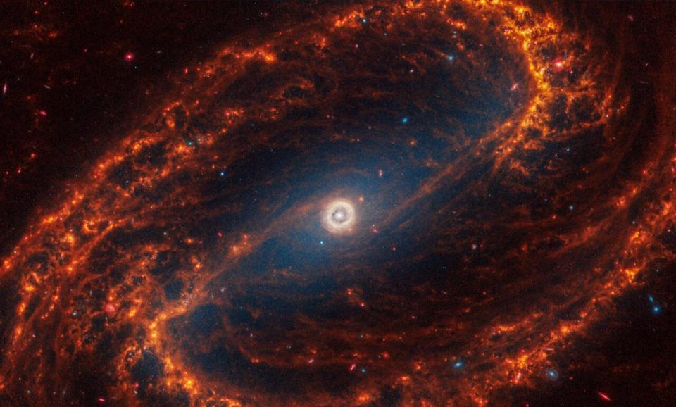 Barred spiral galaxy NGC 1300, with baby red stars at the ends of orange dust lanes