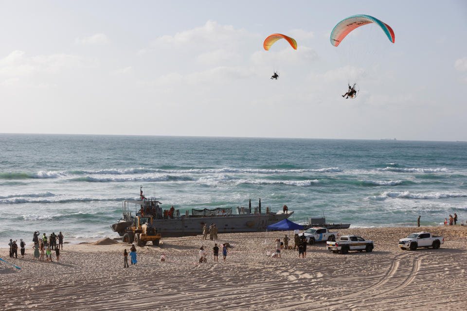 Paragliders pass above U.S. troops working around vessels used for delivering aid to Palestinians via a new U.S.-built pier in Gaza, after they ran aground along the Mediterranean shore in Ashdod, Israel May 25, 2024. Both vessels got stuck after one came to help the other. REUTERS/Amir Cohen     TPX IMAGES OF THE DAY