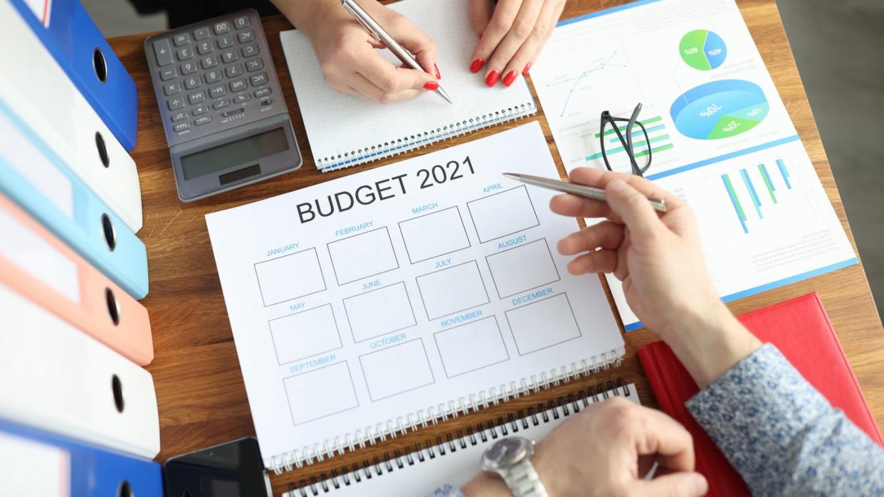 Business man and woman with pens in hands showing charts on document at table in office closeup.