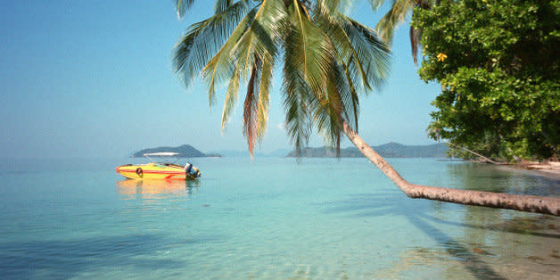 KOH MAK, TRAT, THAILAND - 2003/12/01: A speedboat floats, anchored off a coconut fringed shoreline on Koh Mak, a Thai island paradise.. (Photo by Peter Charlesworth/LightRocket via Getty Images)