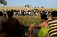 People gather at the site where a passenger train derailed injuring at least 100 people, near Banha, Qalyubia province, Egypt, Sunday, April 18, 2021. At least eight train wagons ran off the railway, the provincial governor's office said in a statement. (AP Photo/Tarek Wagih)