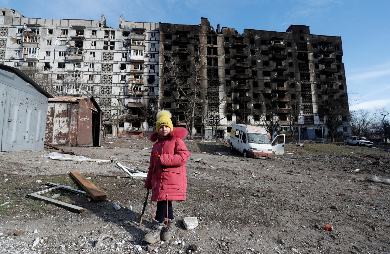 A girl walks in the courtyard of an apartment building destroyed by Russian forces in the besieged southern port city of Mariupol.