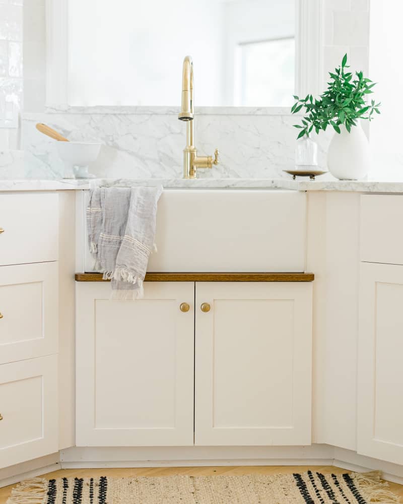 Sink area with brass fittings in remodeled white kitchen