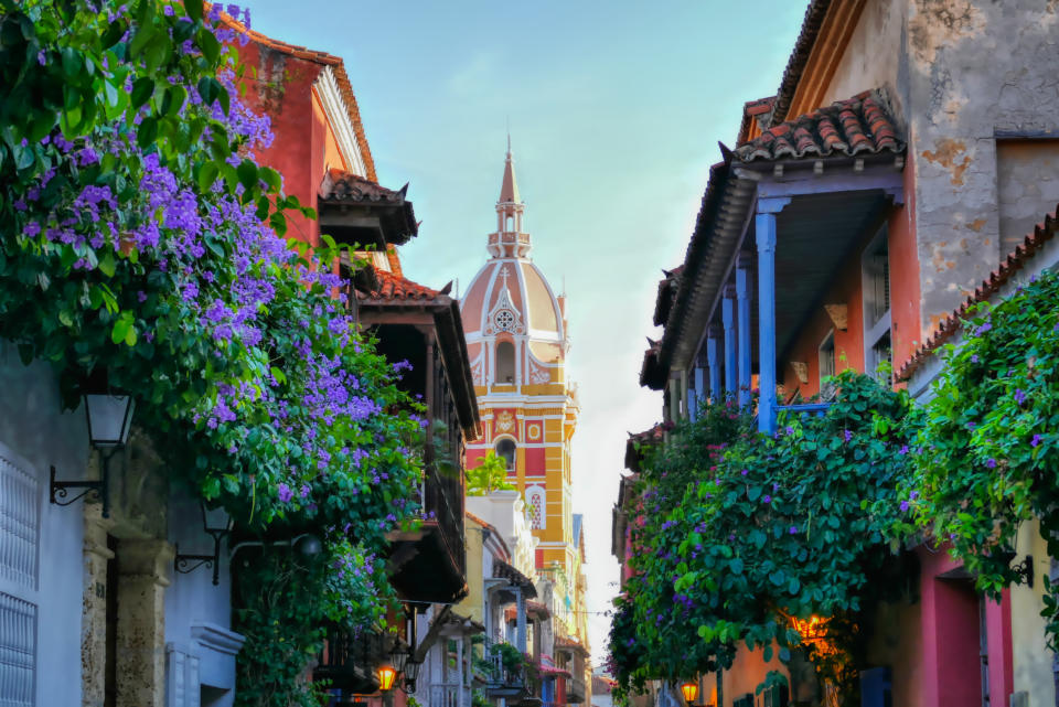 Narrow street with colonial buildings and a church tower in the distance