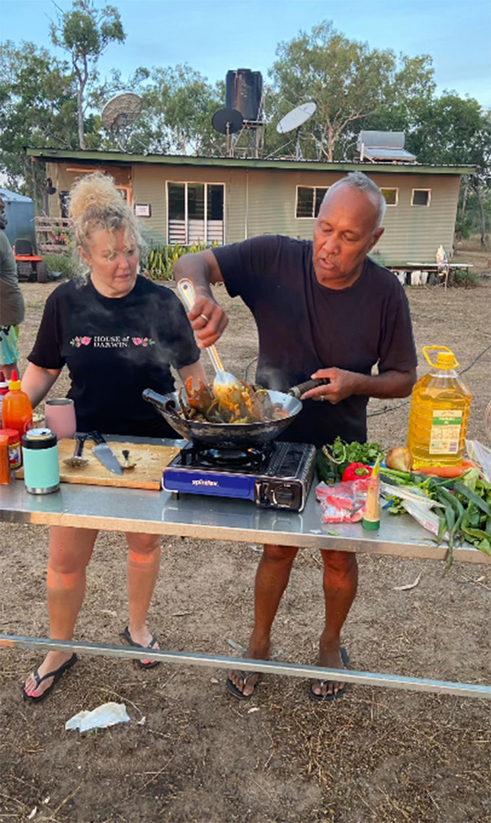 Cath and Robbie from MasterChef cooking together at a camp station