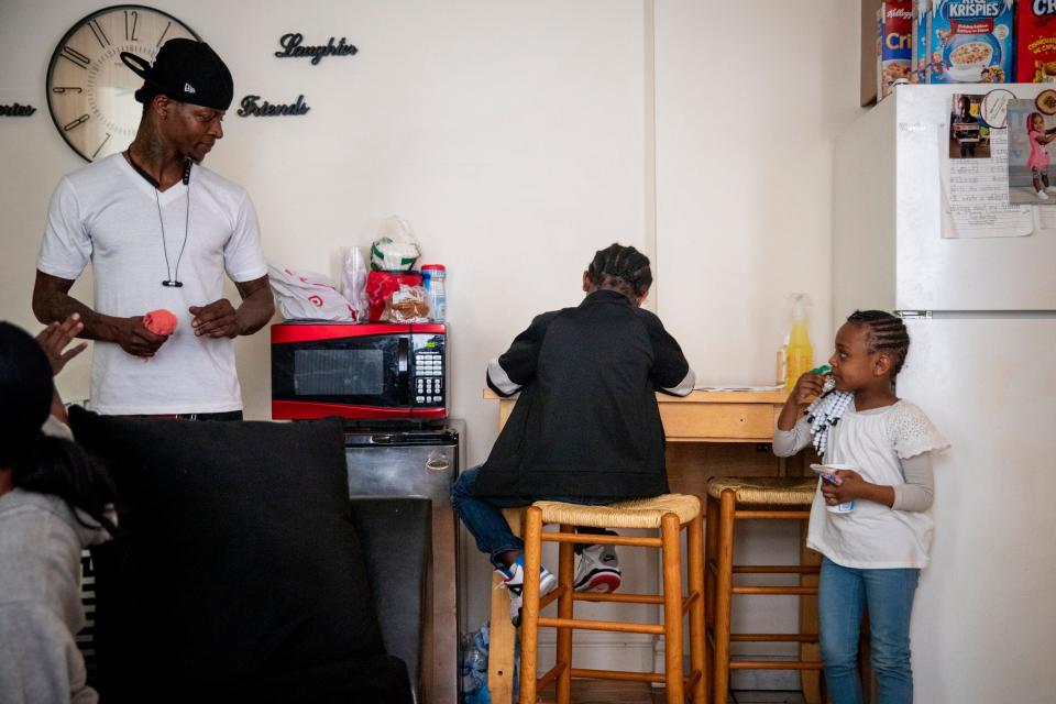 Sinaca Wagoner, Jr. 7, works on his school work while his dad and sister watch in their apartment in Lower Price Hill on Thursday, April 2, 2020. Sinaca Jr. is in the second grade at Cincinnati College Preparatory Academy. 