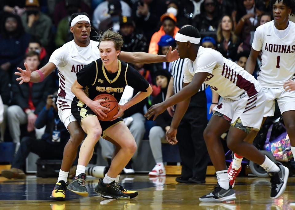 R-H’s Tobey Wright, center, is defended by Aquinas' Myles Blackwood, left, and Mykel White during the Section V Class AA Championship at Gates Chili High School, Saturday, March 5, 2022. No. 2 seed Aquinas No. 8 seed Rush-Henrietta.