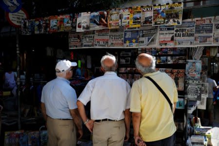 People read newspapers hanging outside a kiosk in Athens, Greece, August 20, 2018. REUTERS/Alkis Konstantinidis