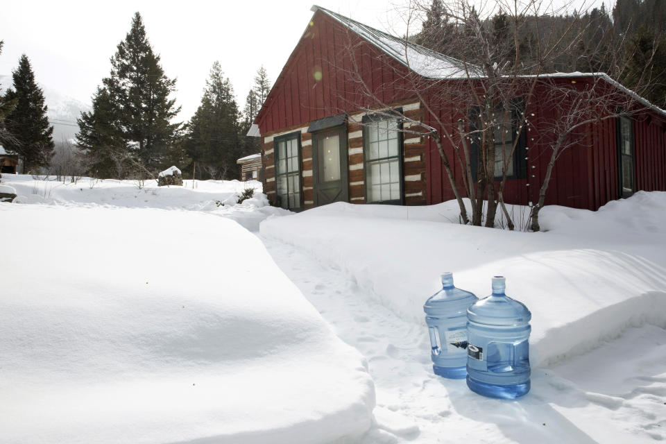 Bottles of drinking water sit outside a home in Rimini, Mont., on Feb. 18, 2019. The community was added to the Environmental Protection Agency's Superfund list in 1999. Contaminated soil in residents’ yards was replaced, and the EPA has provided bottled water for a decade. But polluted water still pours from the mines and into Upper Tenmile Creek. (AP Photo/Janie Osborne)