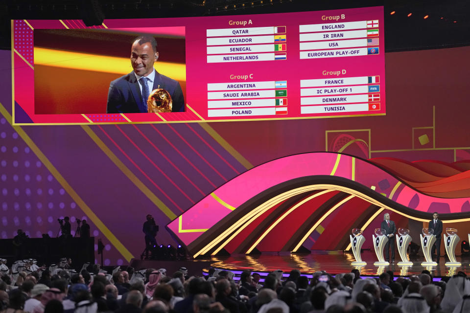 Former Brazilian soccer international Cafu is seen on screen alongside some of the groups during the 2022 soccer World Cup draw at the Doha Exhibition and Convention Center in Doha, Qatar, Friday, April 1, 2022. (AP Photo/Darko Bandic)