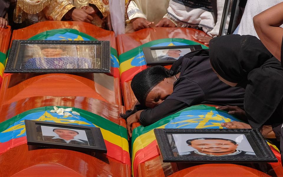 A woman lays on the coffin of her loved one during