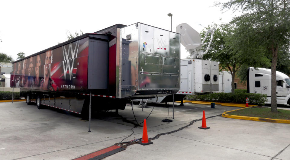 A trailer and a satellite truck to transmit wrestling broadcasts are parked outside the WWE Performance Center Tuesday, April 14, 2020, in Orlando, Fla. Florida’s top emergency official last week amended Gov. Ron DeSantis’ stay-at-home order to include employees at the professional sports and media production with a national audience, if the location is closed to the public. (AP Photo/John Raoux)