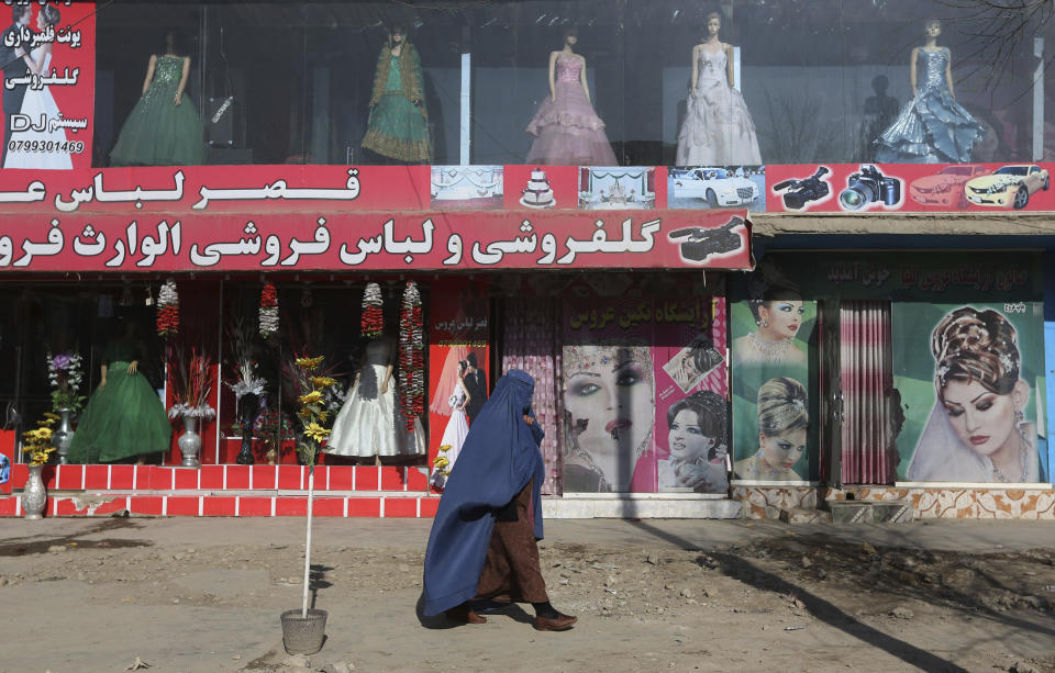 FILE - A woman walks past a beauty salon and dress shop in Kabul, Afghanistan, Sunday, Dec. 13, 2015. A spokesman at Afghanistan's Vice and Virtue Ministry said Tuesday, July 4, 2023, the Taliban are banning women's beauty salons. (AP Photo/Rahmat Gul, File)