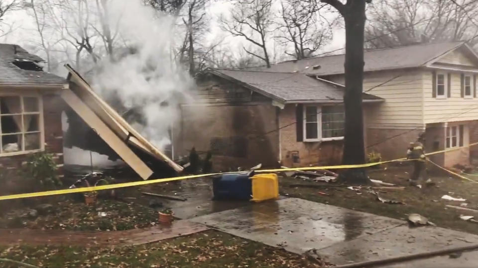 In this image made from video provided by the Prince George's County Fire and Emergency Medical Services Department, a firefighter walks around the scene of a small plane crash in the Lanham neighborhood, Md., Sunday, Dec. 29, 2019. The small plane crashed in the Maryland suburbs of the nation's capital Sunday, hitting a home's carport and killing at least a person aboard the aircraft, authorities said. (Prince George's County Fire/EMS via AP)