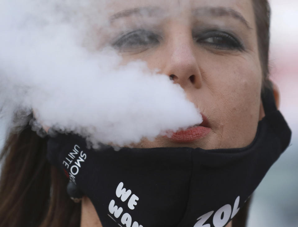 FILE — In this June 2, 2020 file photo, a demonstrator exhales smoke during a protest against the tobacco ban outside parliament in Cape Town, South Africa. South Africa is three months into a ban on the sale of cigarettes and other tobacco products, an unusual tactic employed by a government to protect the health of its citizens during the coronavirus pandemic. The country is one of just a few around the world to have banned tobacco sales during the pandemic and the only one to still have it in place. (AP Photo/Nardus Engelbrecht/File)