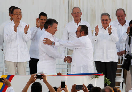 Colombian President Juan Manuel Santos (L) and Marxist rebel leader Timochenko shake hands after signing an accord ending a half-century war that killed a quarter of a million people, in Cartagena, Colombia September 26, 2016. REUTERS/John Vizcaino