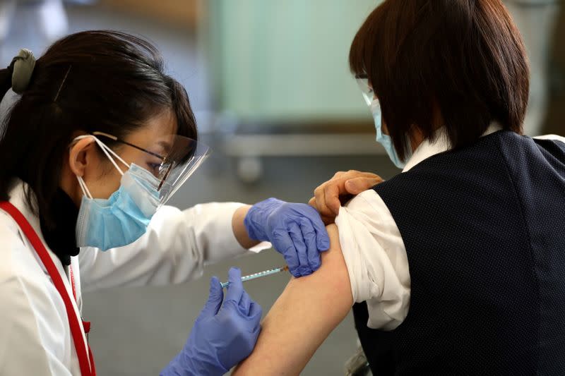 A medical worker receives a dose of the coronavirus disease (COVID-19) vaccine as the country launches its inoculation campaign, in Tokyo