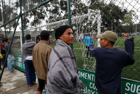 A group of migrants from Honduras, part of a caravan traveling from Central America en route to the United States, watch a local football game outside a sports centre used as a shelter in Mexico City, Mexico November 4, 2018. REUTERS/Henry Romero