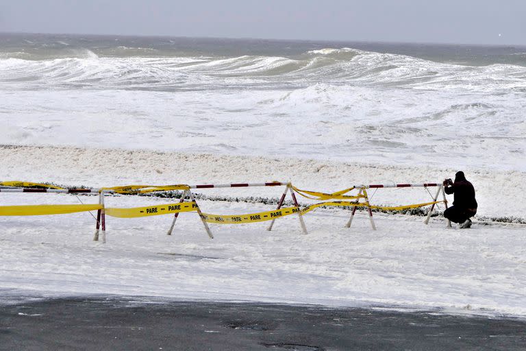 A man takes pictures of foam and sea spray covering the sea front promenade during the passage of a subtropical cyclone in Punta del Este, Uruguay, on May 17, 2022. (Photo by RICARDO FIGUEREDO / AFP)