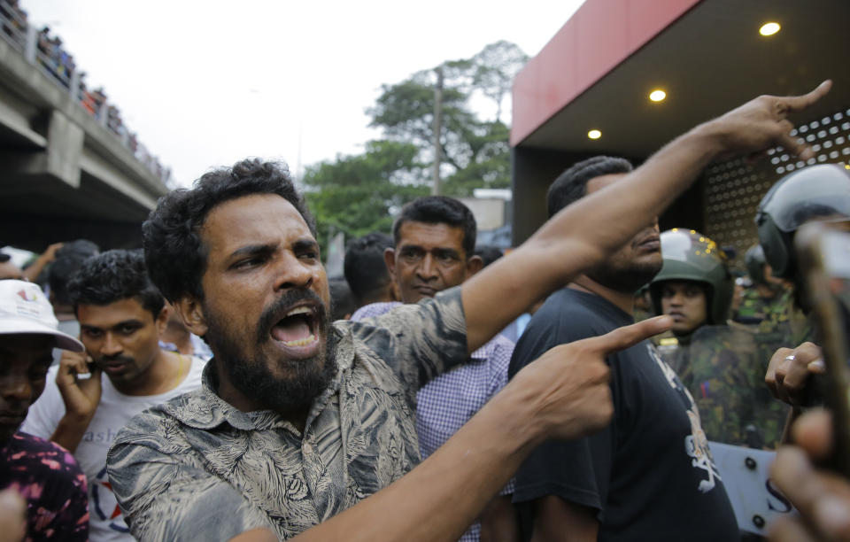 A supporter of newly appointed Sri Lankan prime minister Mahinda Rajapaksa shouts at police officers outside petroleum ministry building in Colombo, Sri Lanka, Sunday, Oct. 28, 2018. Arjuna Ranatunga who was petroleum minister under Wickremesinghe said one of his security guards opened fire when Rajapaksa supporters mobbed him and protested against him entering the ministry premises. (AP Photo/Eranga Jayawardena)