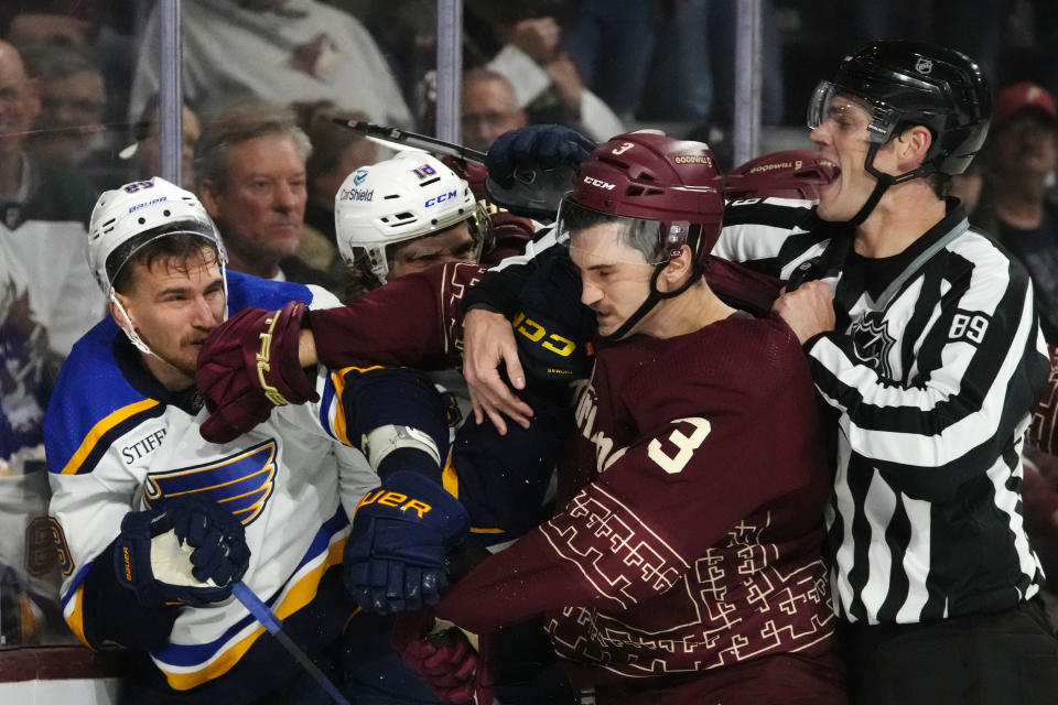 Linesman Joe Mahon (89) tries to break up a scuffle between Arizona Coyotes defenseman Josh Brown (3), St. Louis Blues left wing Pavel Buchnevich, left, and Blues center Robert Thomas (18) during the second period of an NHL hockey game Saturday, Dec. 2, 2023, in Tempe, Ariz. (AP Photo/Ross D. Franklin)