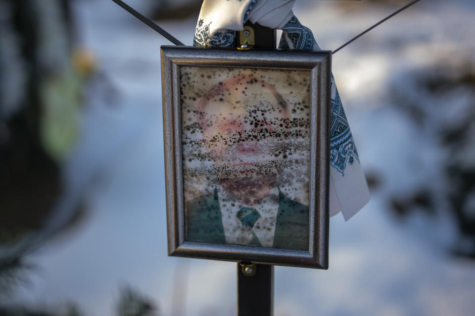 A worn-out portrait of Petro Vasylovych, 57, sits on his grave at a cemetery in Irpin, Ukraine, on the outskirts of Kyiv, on Thursday, Feb. 9, 2023. He was buried on May 5, 2022. (AP Photo/Emilio Morenatti)