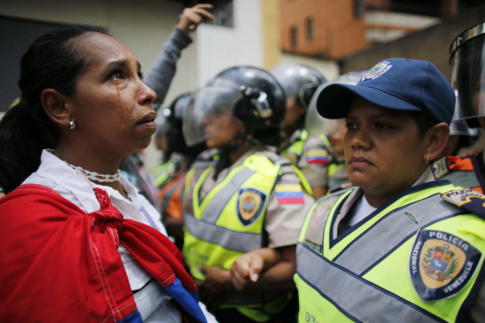 <p>A demonstrator stands in front of policewomen blocking an opposition march from reaching the Interior Ministry in Caracas, Venezuela, May 6, 2017. Thousands of women wearing white and carrying flowers marched to ask for a stop of repression and to pay tribute to those who were killed in weeks of near-daily violent protests calling on President Nicolas Maduro to step down. (Photo: Ariana Cubillos/AP) </p>