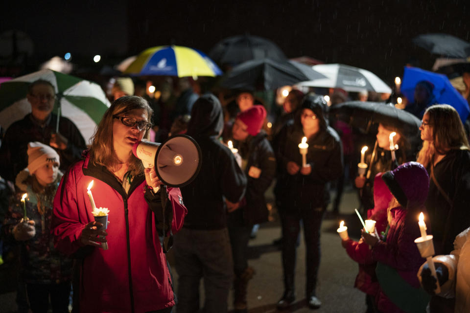 Sherri Jasper, a Girl Scout board member and counselor at Halmstad Elementary School, leads the program for a candlelight vigil at the school in Chippewa Falls, Wis., Sunday evening, Nov. 4, 2018. The western Wisconsin community on Sunday was grieving the deaths of three Girl Scouts and a parent who were collecting trash Saturday along a rural highway when police say a pickup truck veered off the road and hit them before speeding away. The 21-year-old driver, Colten Treu of Chippewa Falls, sped off but later surrendered. He will be charged with four counts of homicide, Lake Hallie police Sgt. Daniel Sokup said. (Jeff Wheeler/Star Tribune via AP)