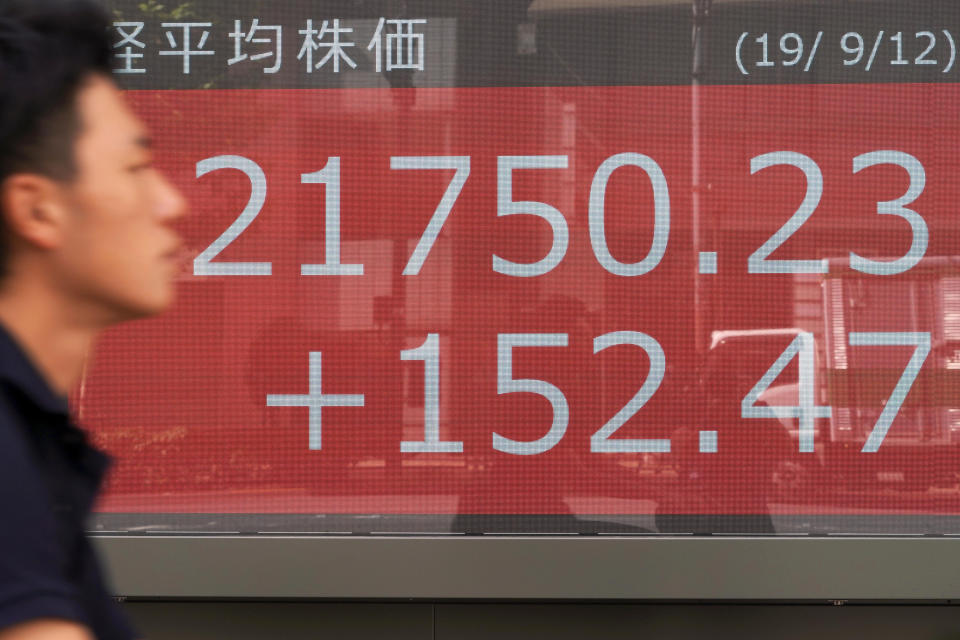 A man walks past an electronic stock board showing Japan's Nikkei 225 index at a securities firm in Tokyo Thursday, Sept. 12, 2019. Asian shares were mixed Thursday after China moved to ease trade tensions. (AP Photo/Eugene Hoshiko)