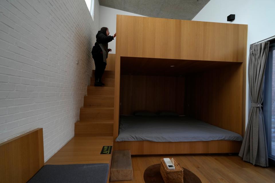 A local resident hired as a cleaner for a traditional courtyard house turned into lodging for tourists inspects one of the rooms in Houheilong Miao, a village in Yanqing on the outskirts of Beijing, China, Wednesday, Jan. 5, 2022. The village has a view of the Olympics skiing venue in the distance. Its 20 mostly vacant traditional courtyard houses have been turned into lodgings and a cafe dubbed the "Winter Olympic Home."