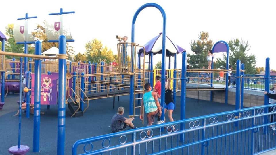 Teens and children play on the playground at Settlers Park. A site west of the park that was set aside for a school is now planned for a community center instead.