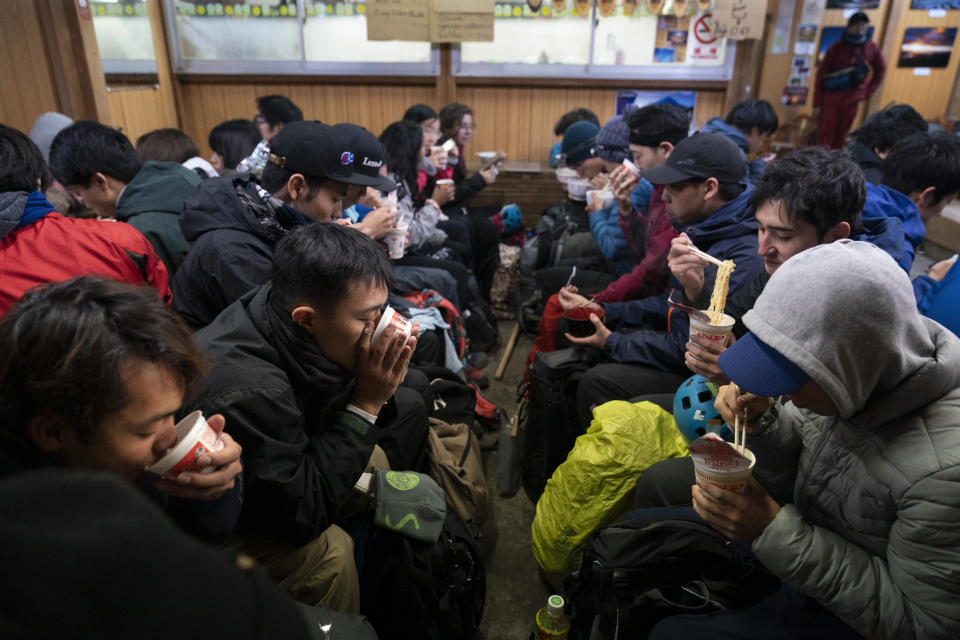 Waiting for the sunrise, climbers eat noodles in a restaurant located on the summit of Mount Fuji, Tuesday, Aug. 27, 2019, in Japan. (AP Photo/Jae C. Hong)