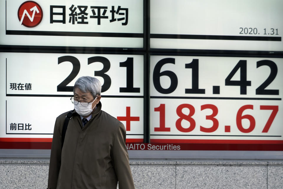 A man walks past an electronic stock board showing Japan's Nikkei 225 index at a securities firm in Tokyo Friday, Jan. 31, 2020. Shares are mixed in Asia after the World Health Organization declared the outbreak of a new virus that has spread from China to more than a dozen countries a global emergency. (AP Photo/Eugene Hoshiko)