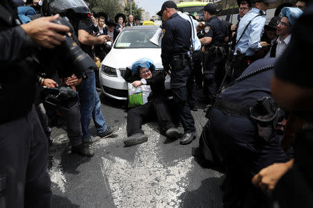 An ultra-Orthodox Jewish man sits on a road as he takes part in a protest against the detention of a fellow community member who evaded a military draft order, in Jerusalem August 2, 2018. REUTERS/Ammar Awad